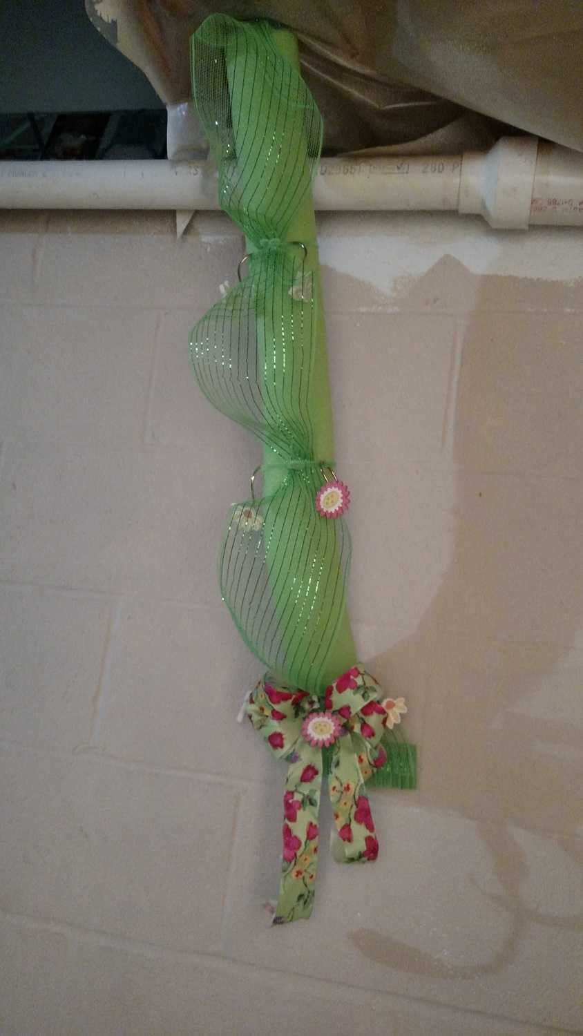 pipe disguised with pool noodle, deco mesh, flower shower curtain hooks, and a bow