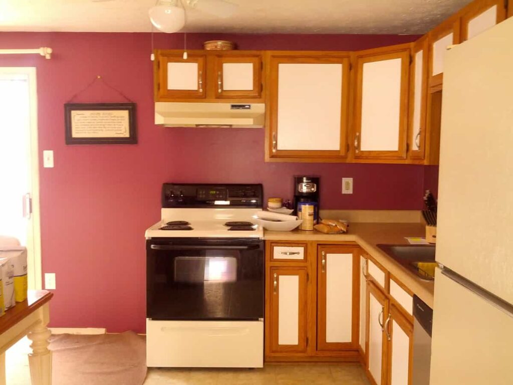 kitchen wall facing stove, with cabinets and red wall