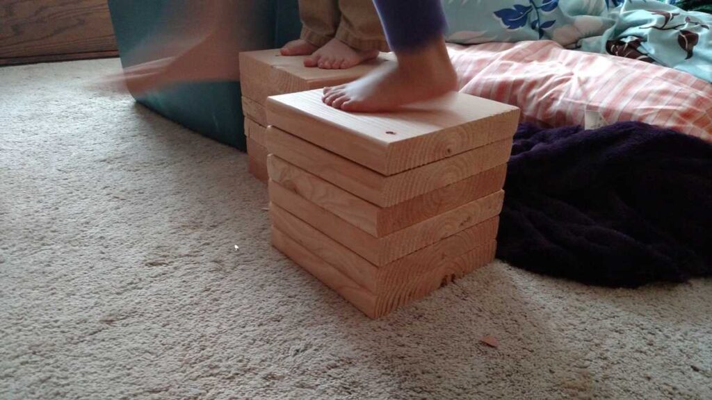 stack of wooden block with children's feet standing on them