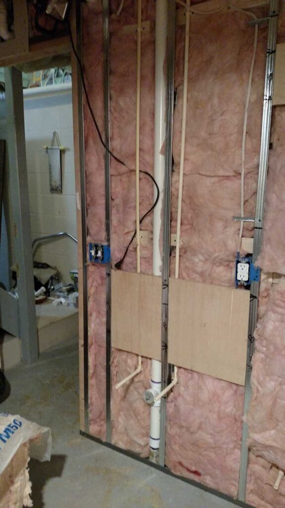 Downstairs Bathroom Part 3 https://www.b4andafters.com bathroom wall showing insulation, electrical wiring, and water pipes exposed