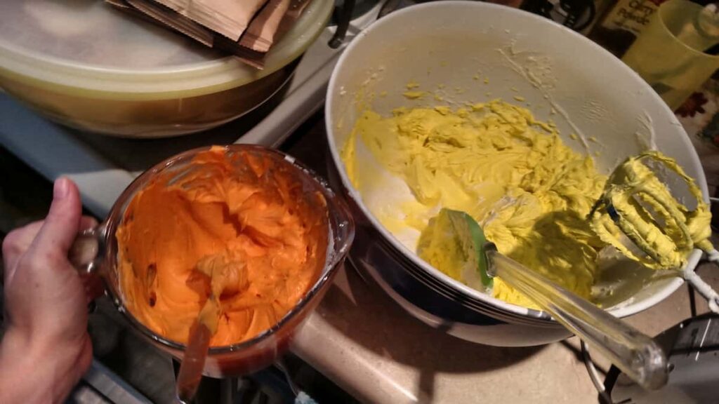 a bowl of orange frosting, and a bowl of yellow frosting