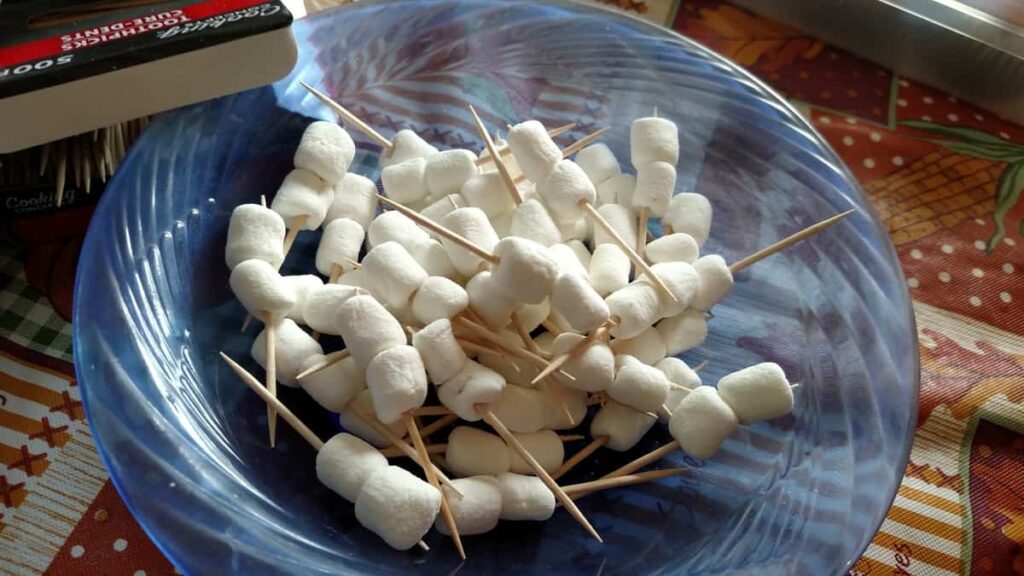 a bowl full of miniature marshmallows on toothpicks