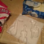 clear plastic mold for saxophone, violin, trumpet, and keyboard with pink candy melts and white almond bark in packages