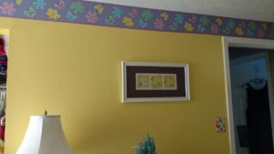 girls room painted yellow with flower wallpaper border near ceiling