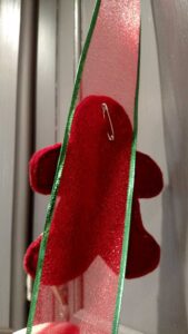 safety pin on back of felt gingerbread boy holding it to ribbon