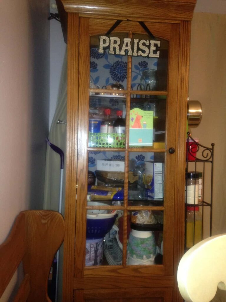 the front of a tall glass window cabinet with kitchen supplies in it