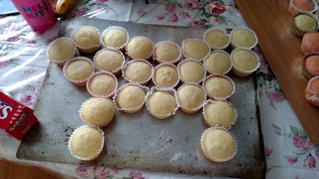 24 vanilla cupcakes arranged in the shape of a horse on a cookie sheet