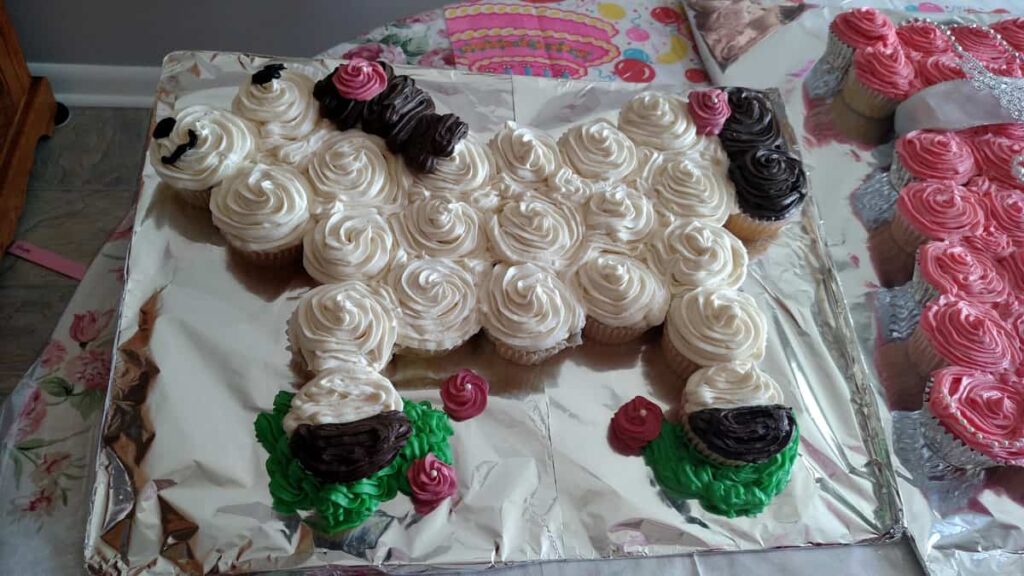 white frosted cupcakes in the shape of a horse, with green grass detail and some pink flowers