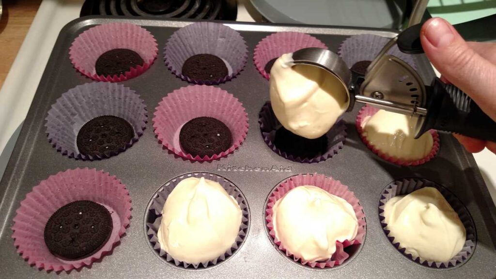 Mini Oreo Crust Cheesecakes https://www.b4andafters.com scooping cream cheese mixture into cupcake liners