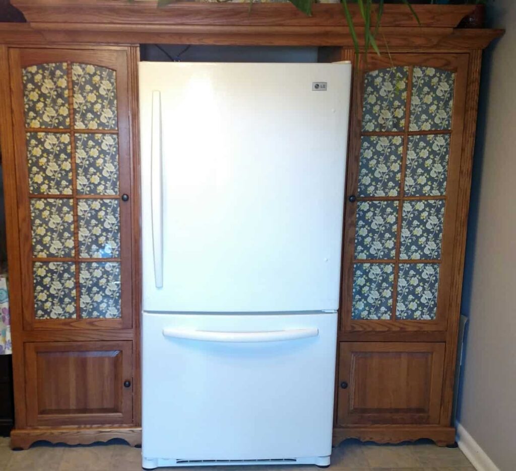 the fridge in its new place between the entertainment center cupboards 