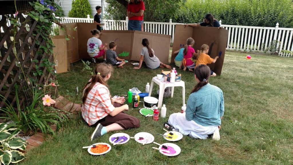 party goers painting the large cardboard scenes