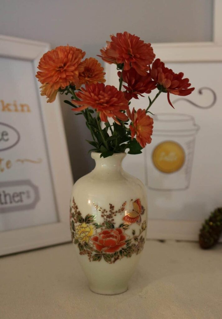 orange mums in a miniature vase