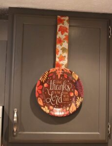 Thanksgiving paper plate and ribbon on a kitchen cupboard