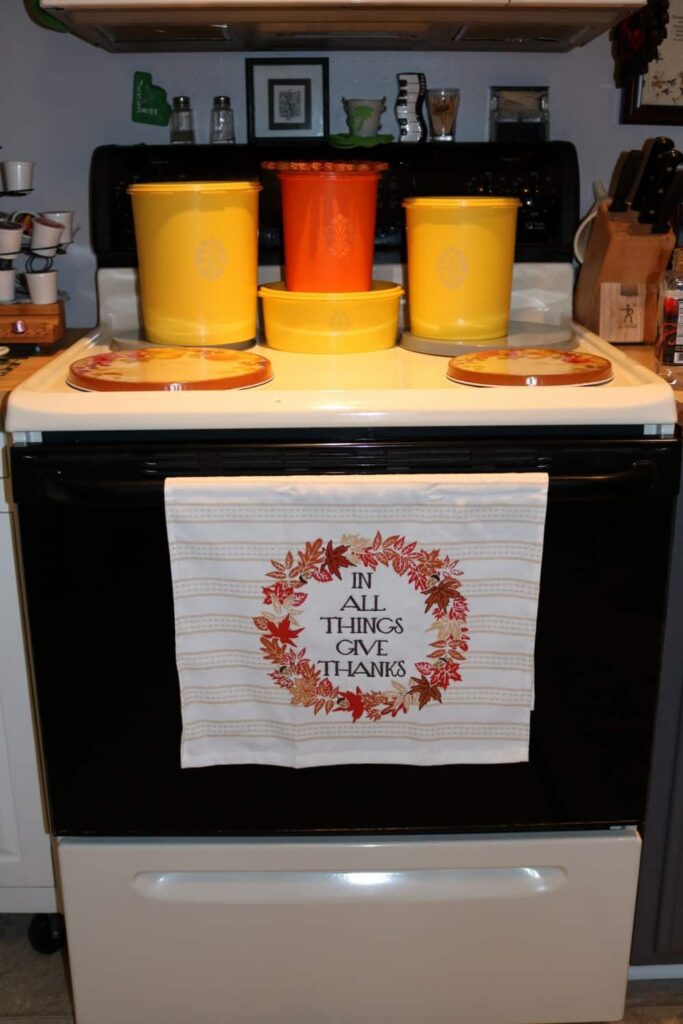 In All Things Give Thanks kitchen towel with yellow and orange vintage Tupperware canisters