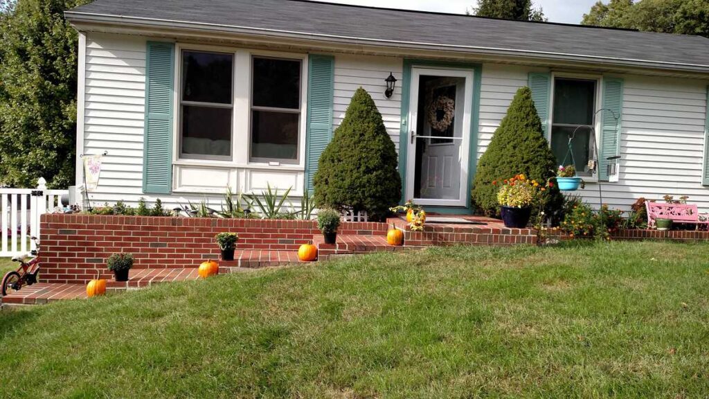 mums and pumpkins lining the brick steps in front a house