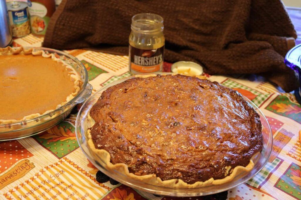 whole pie with empty caramel jar in background