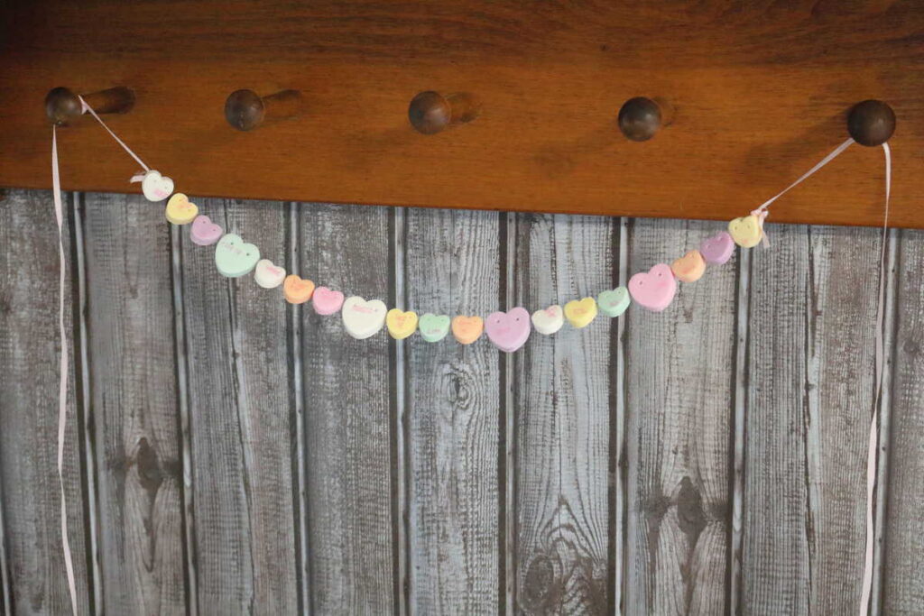 conversation heart garland tied to peg shelf for Valentine's day decor https://www.b4andafters.com/conversation-heart-necklace