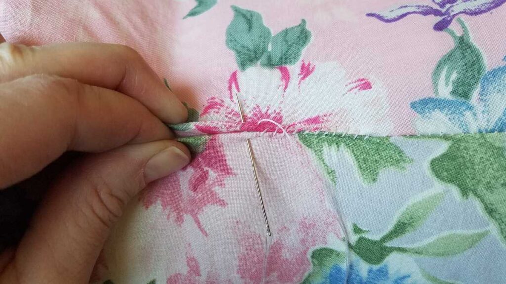 another closeup of sewing the opening closed on a pillow