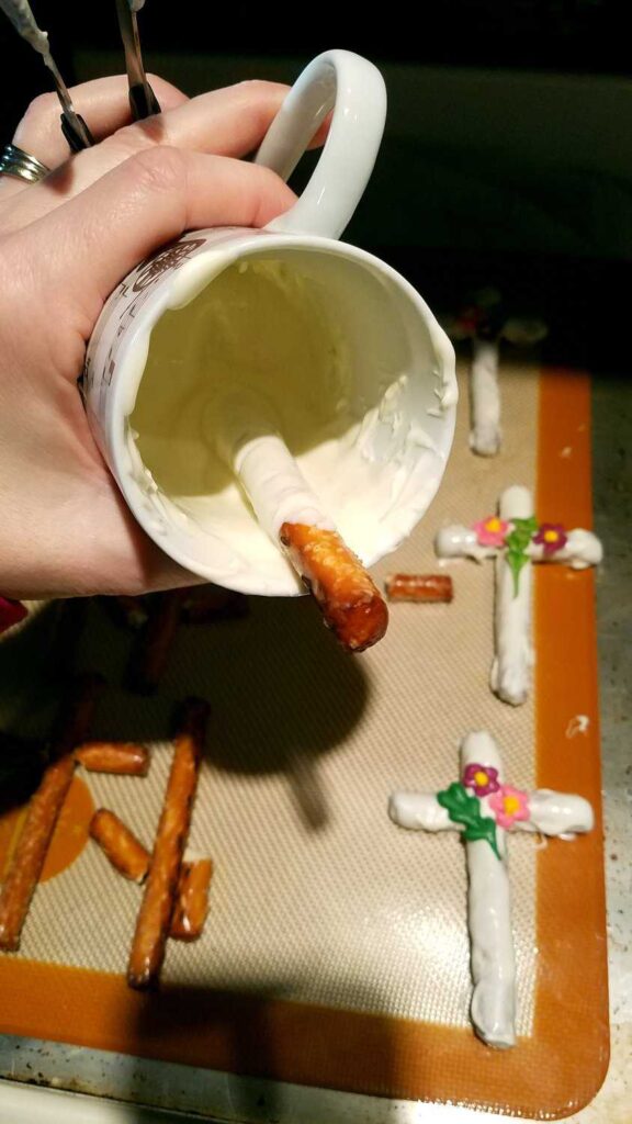 coating a pretzel rod in a mug with white chocolate