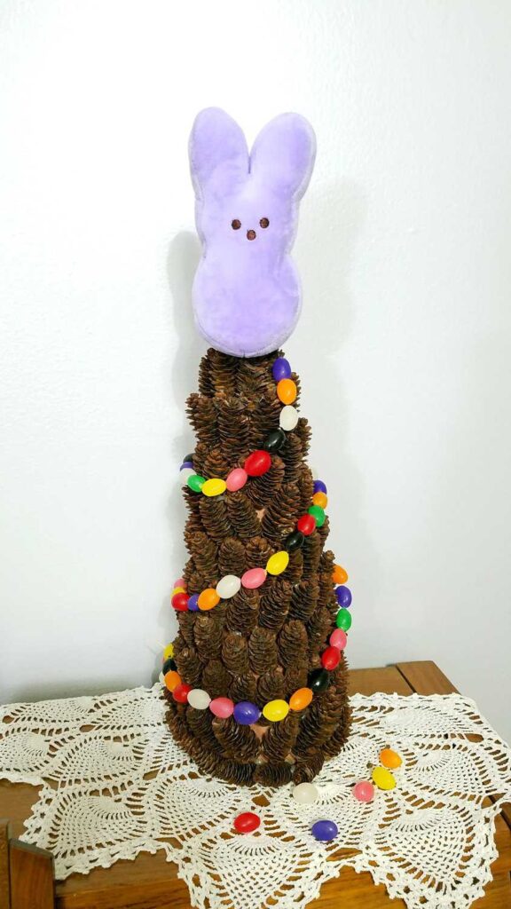 plush bunny Peep on a pine cone tree draped with a jelly bean garland