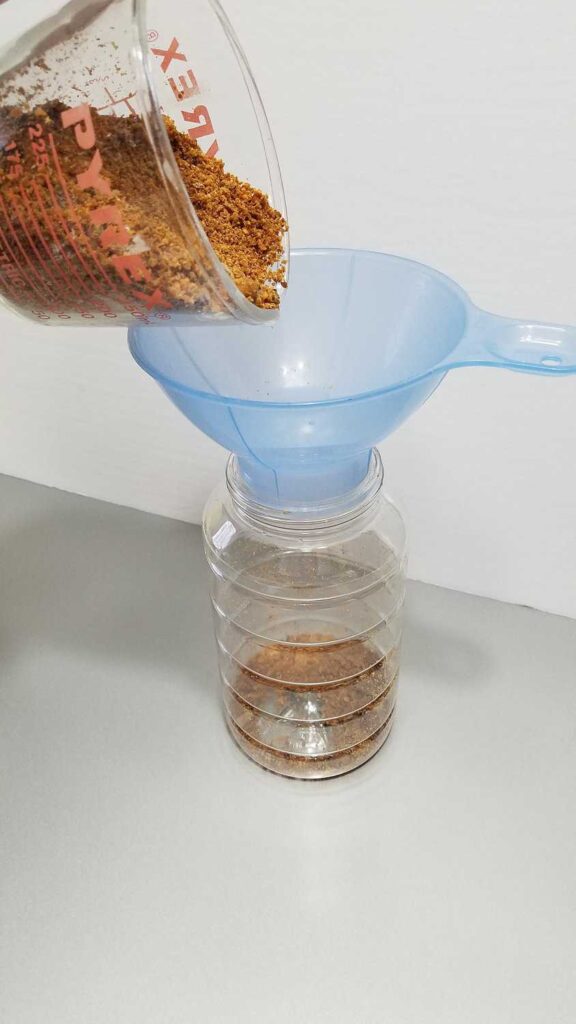 bacon bits being poured through a wide mouth blue funnel into a clear container