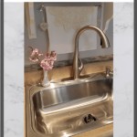 pull down kitchen faucet with pink flowers in a vase beside it