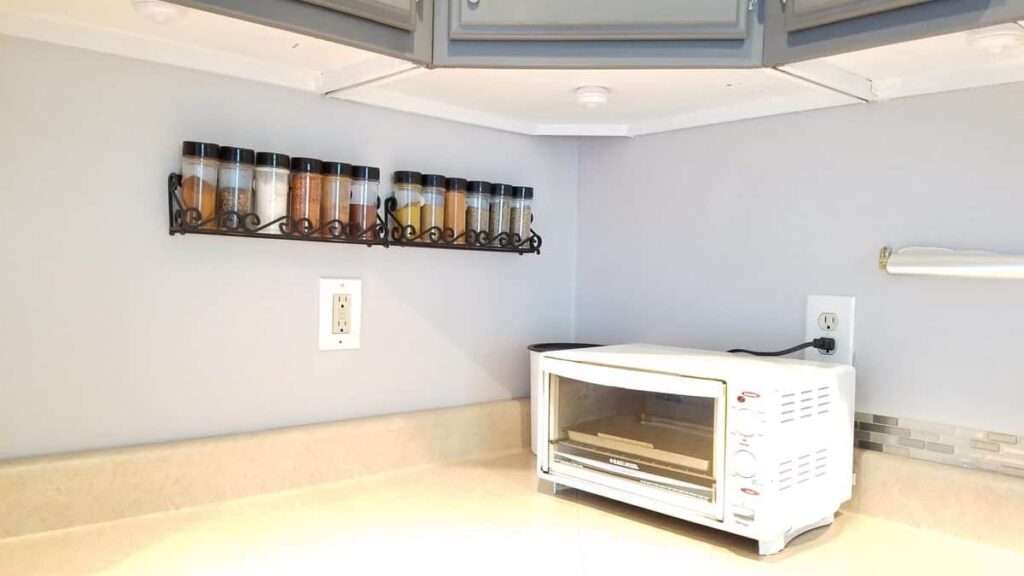 painted white underside of upper kitchen cabinets, also spice bottles on wall, and toaster on counter