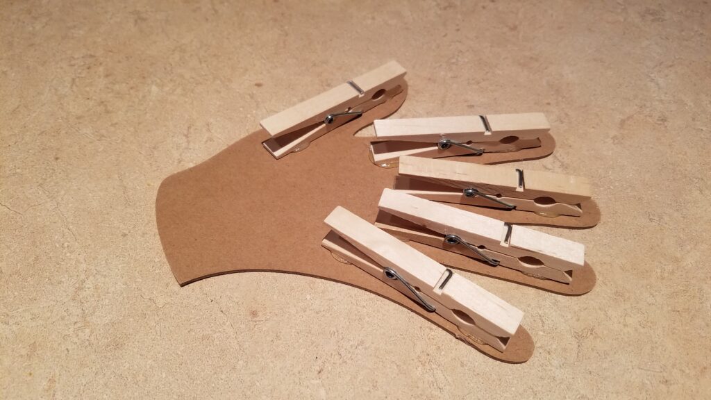 five clothespins all glued to fingers of cut out hand