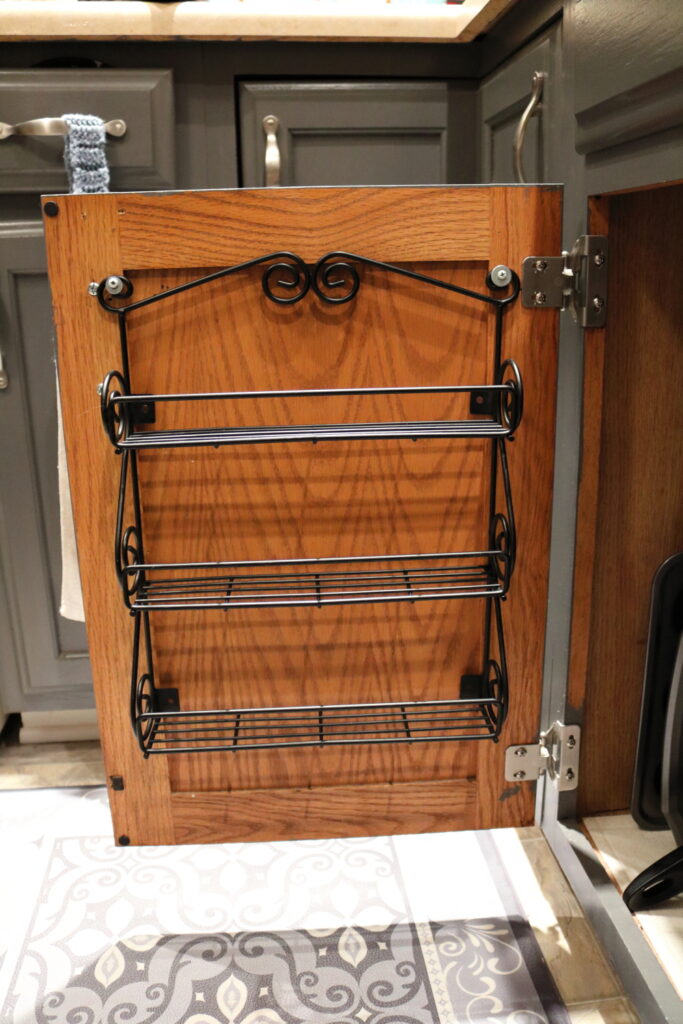 three shelf metal spice rack on inside of kitchen cabinet door