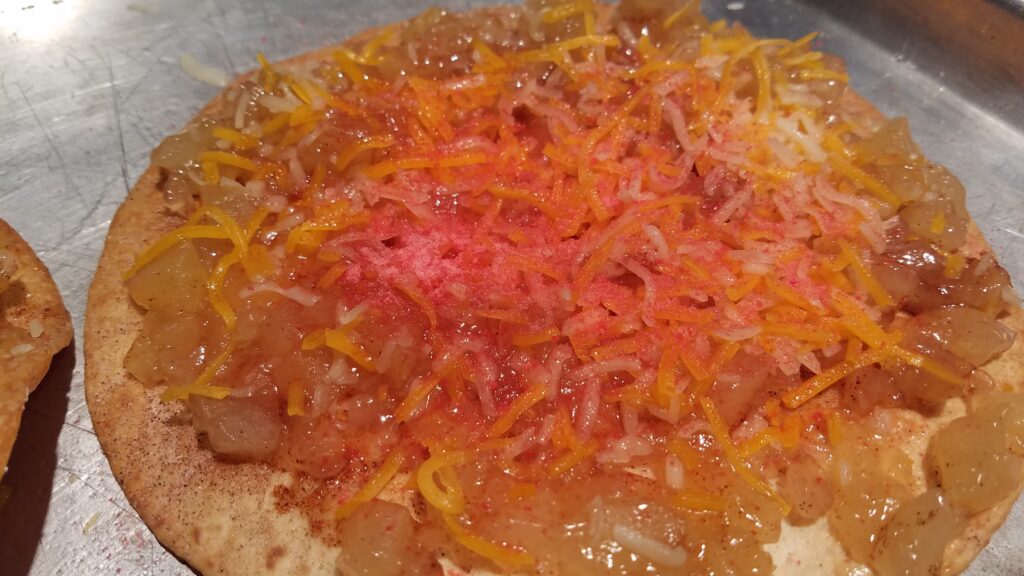 bright pink with orange cheese on apple filling on a cinnamon sugar tortilla
