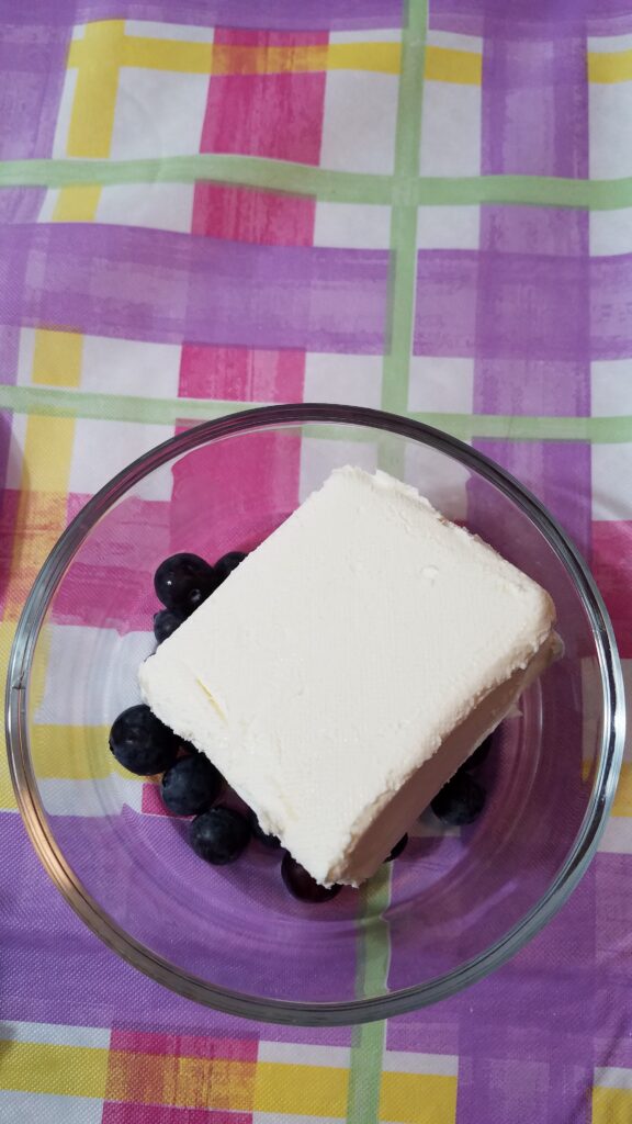 half a brick of cream cheese on top of some fresh blueberries