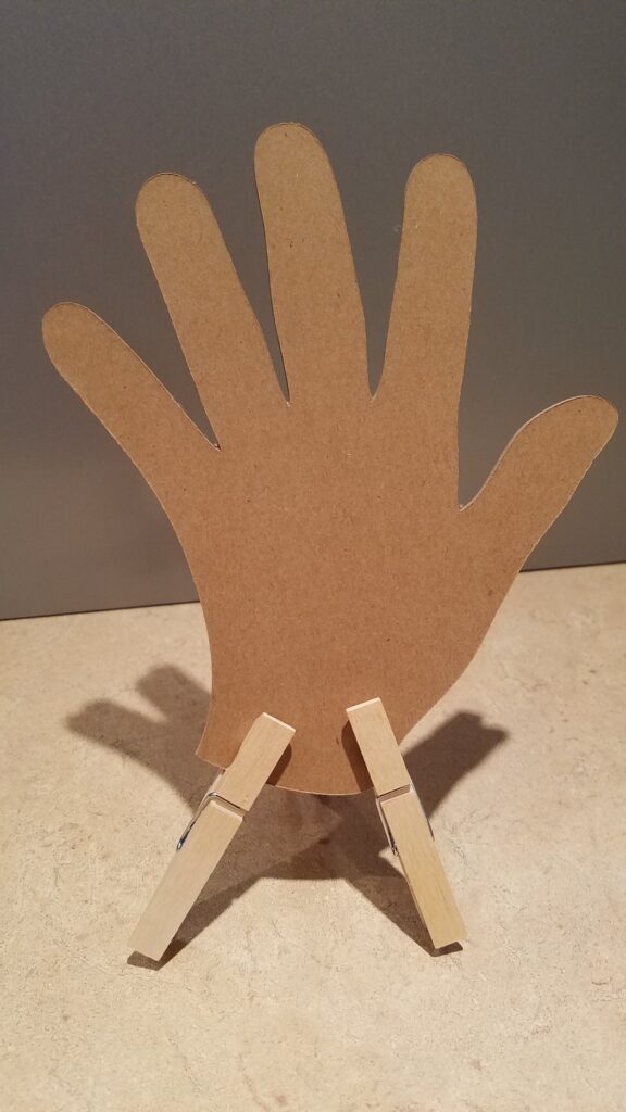 cut out hand propped up with two clothespins