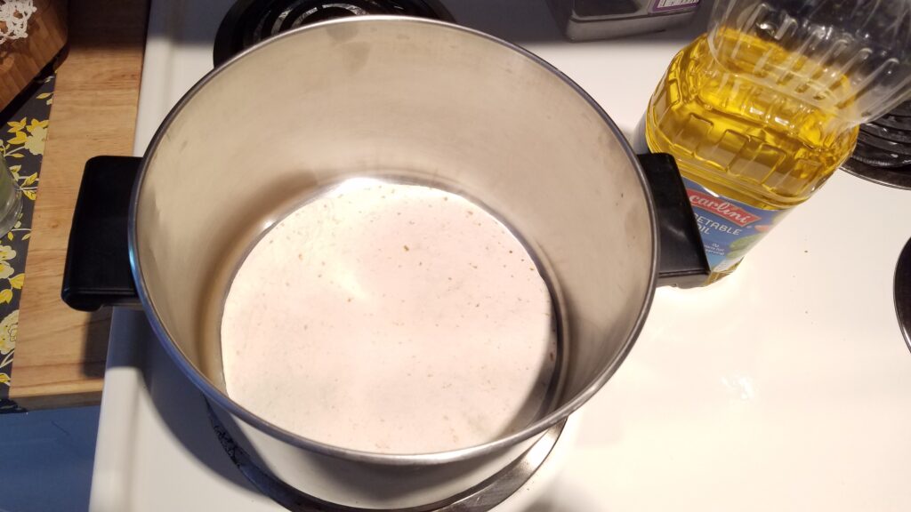 pot on stove with flour tortilla in it, and oil to the side in a bottle