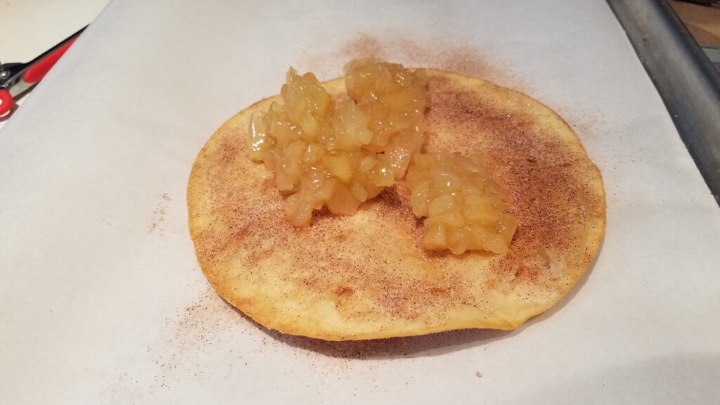 two large spoonfulls of apple pie filling on cinnamon sugar tortilla