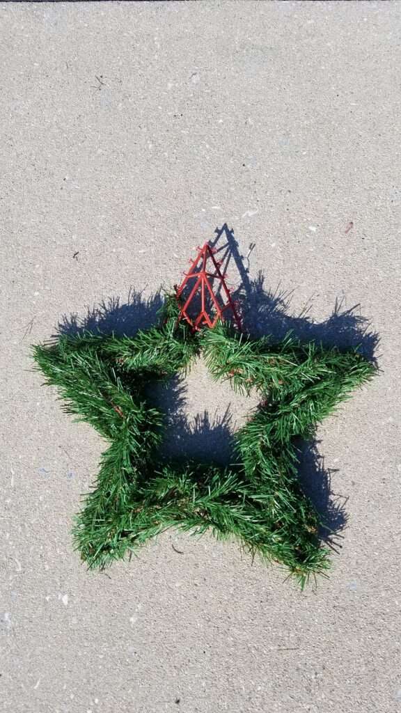 greenery star shaped wreath with one corner exposed showing plastic wreath form