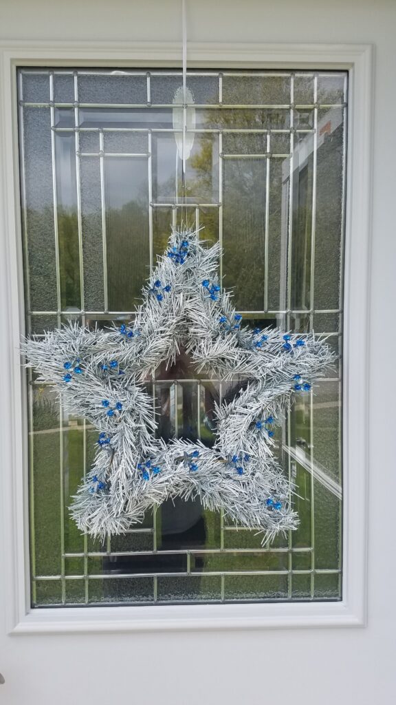 white star shaped wreath hanging on glass window door