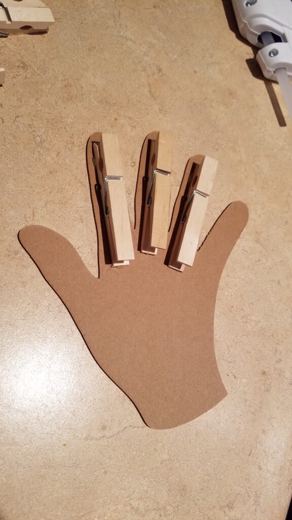 3 clothespins hot glued to chipboard hand