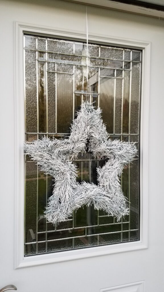 5 point star shaped white wreath hanging on door with glass window