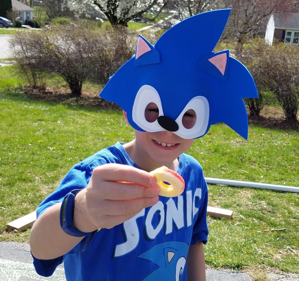 boy wearing a sonic the hedgehog face mask holding a gummy ring