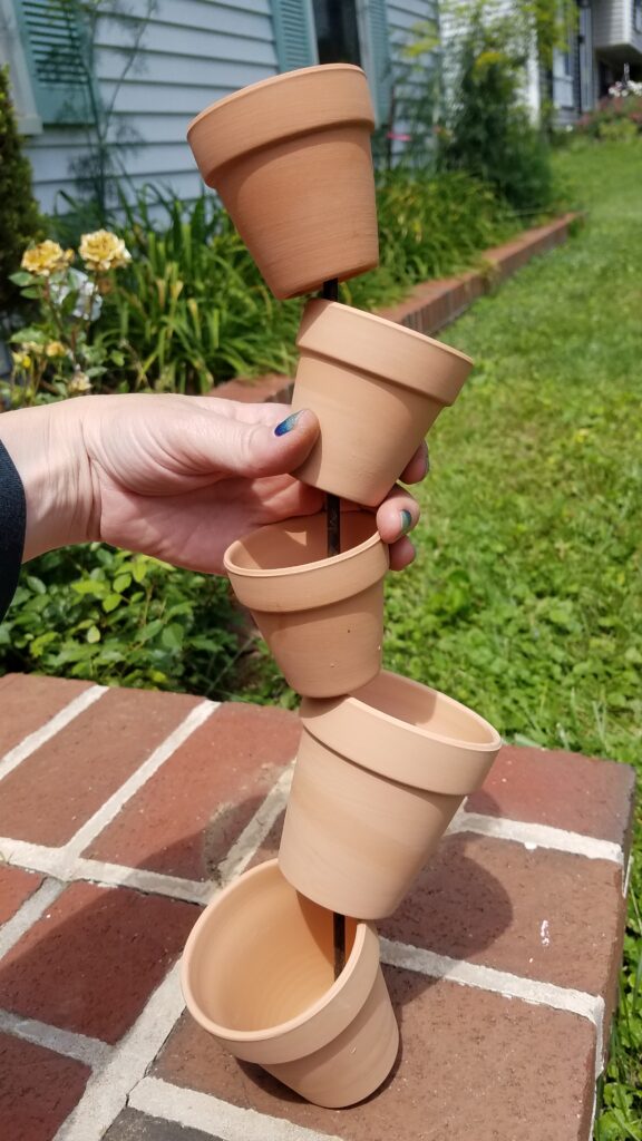 5 miniature terra cotta pots stacked and leaning alternately