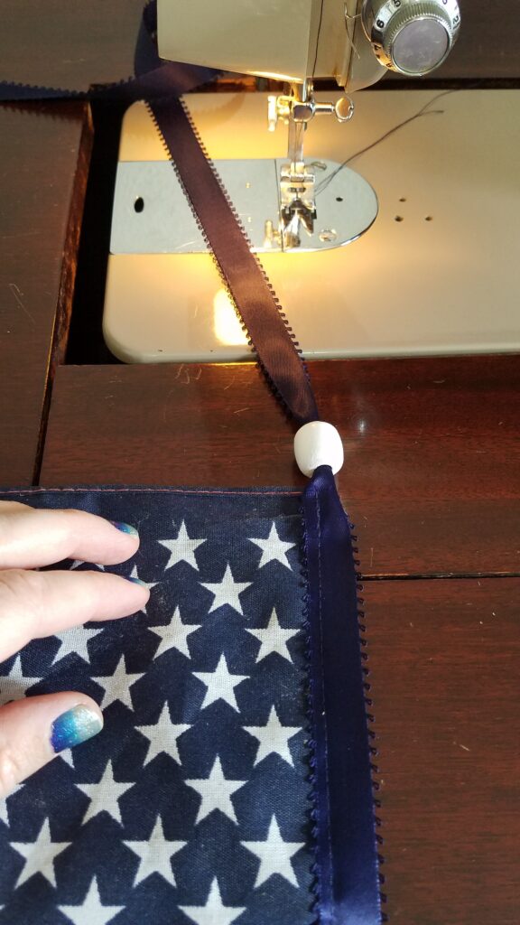 white bead on navy ribbon near sewing machine