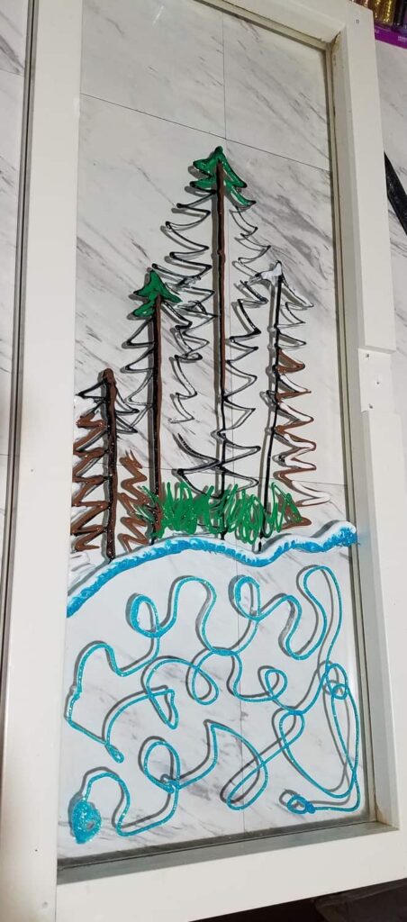 tree outline of winter window scene, with blue pond in glitter paint