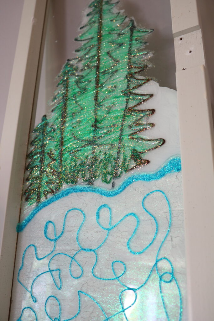 closeup of sparkly glitter paint in winter scene painted onto window