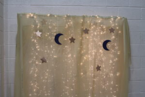 backdrop lit with white Christmas lights, and stars and moons hanging