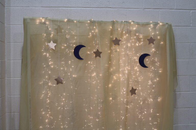 backdrop lit with white Christmas lights, and stars and moons hanging