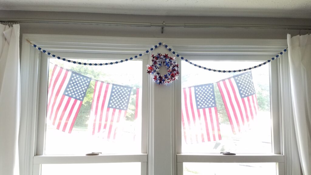 flag banner outside windows with blue and white bead garland and star wreath inside windows