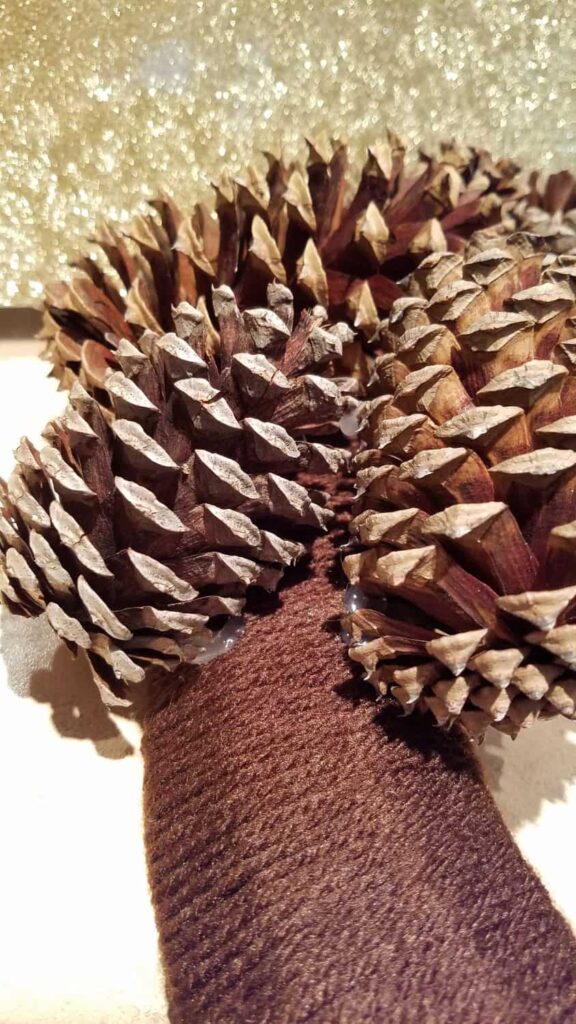 pine cones hot glued onto yarn covered wreath form