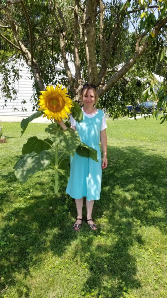 me holding a huge gigantic enormous sunflower that I grew