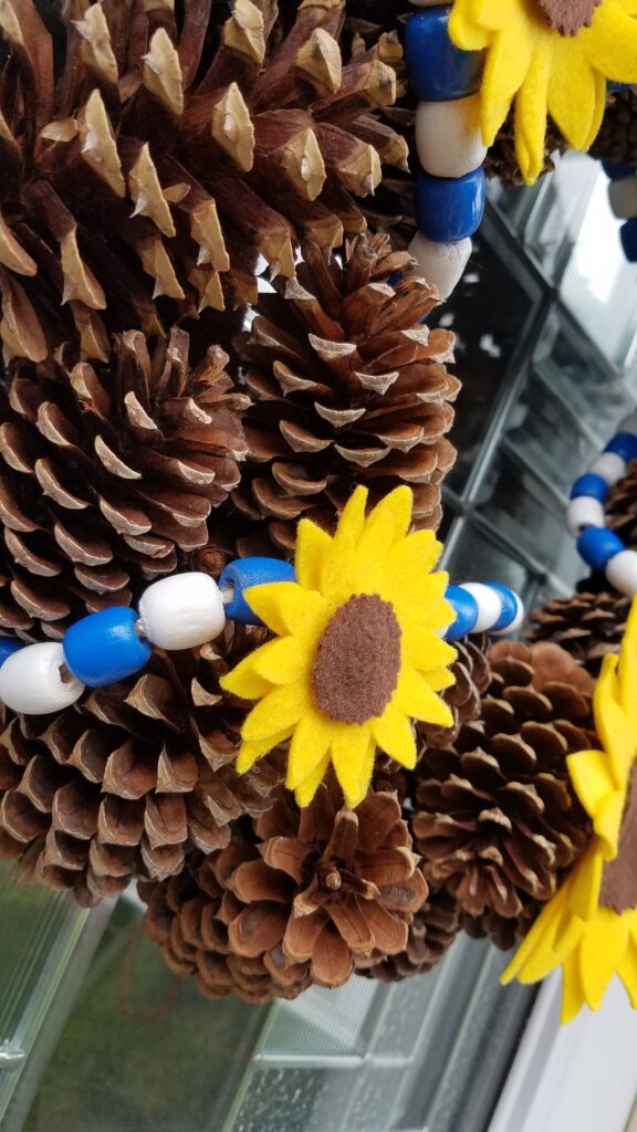 closeup of felt sunflower on pine cone wreath