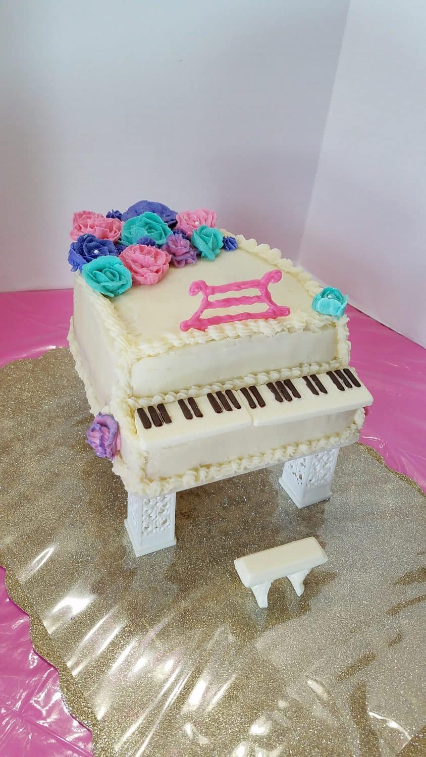 white grand piano cake with blue, pink, and purple flowers
